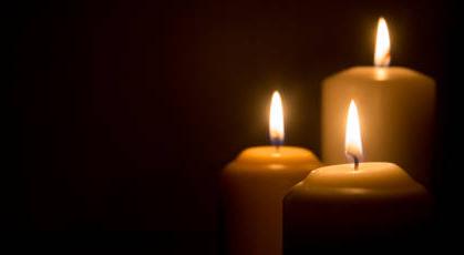In Memoriam three lighted candles on dark background